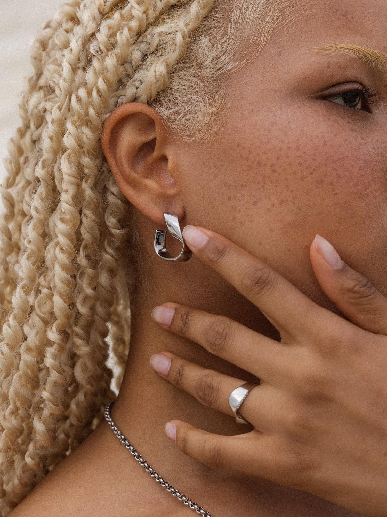 PURELEI River Ohrringe aus silberfarbenem Edelstahl mit geschwungenem Möbiusband, elegant und zeitlos getragen.
