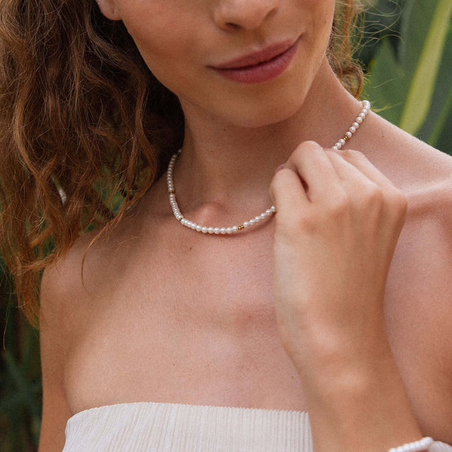 Perlenkette von PURELEI in sanften Tönen, getragen mit tropischem Flair.