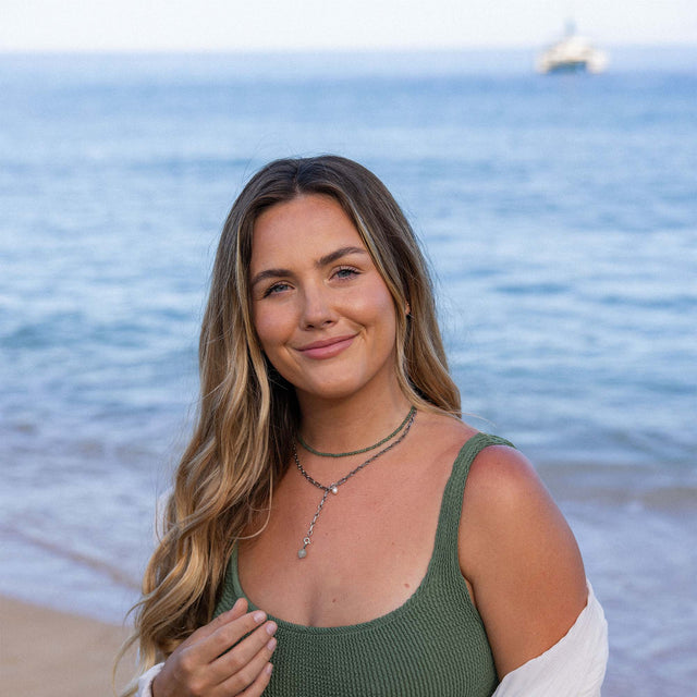 PURELEI Aventurine Charm mit goldfarbenem Anhänger und grünem Stein, natürlich und elegant am Strand getragen.