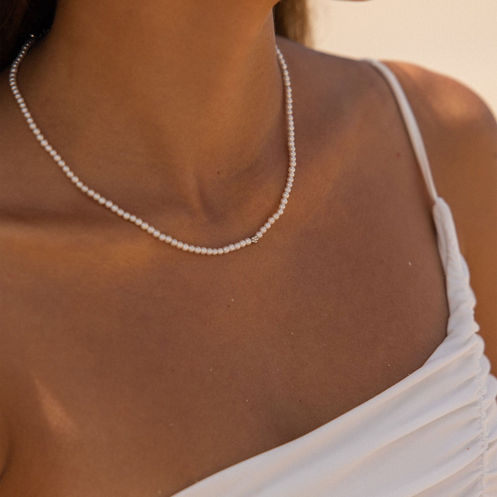 Elegante PURELEI Perlenkette in strahlendem Weiß, getragen mit einem weißen Top.