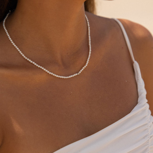 Elegante PURELEI Perlenkette in strahlendem Weiß, getragen mit einem weißen Top.