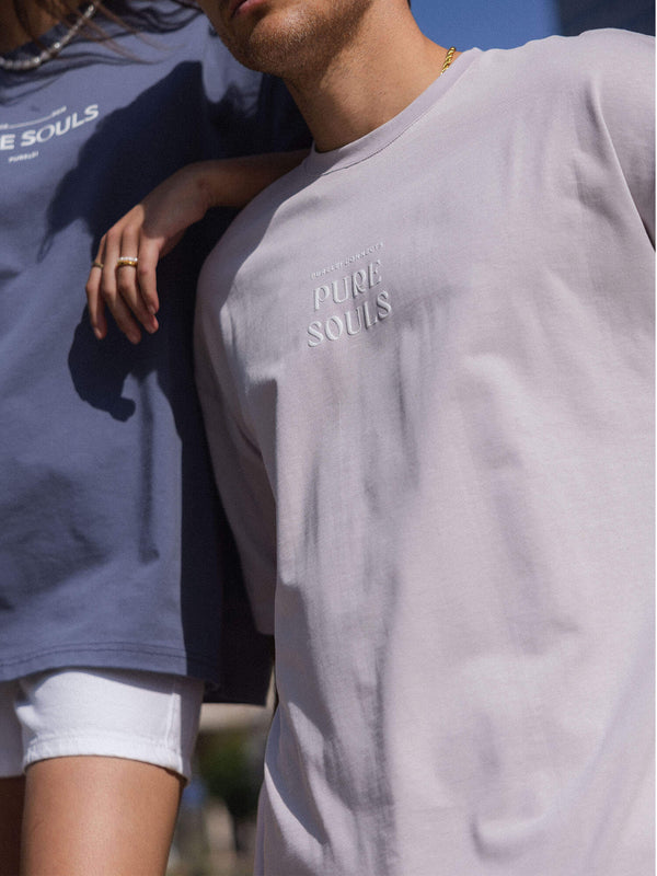 Beige und blaue T-Shirts mit PURELEI-Logo, lässig und modern in sonniger Atmosphäre.