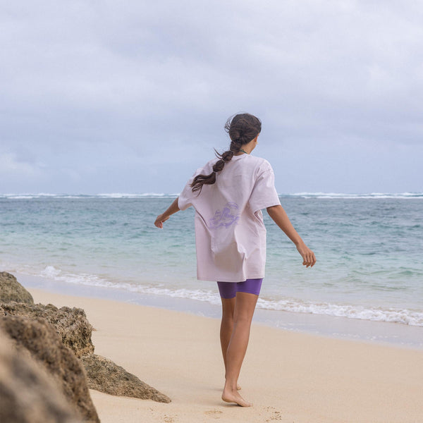 Beige T-Shirt mit maritimem Design, getragen am Strand – PURELEI Aloha-Vibes.