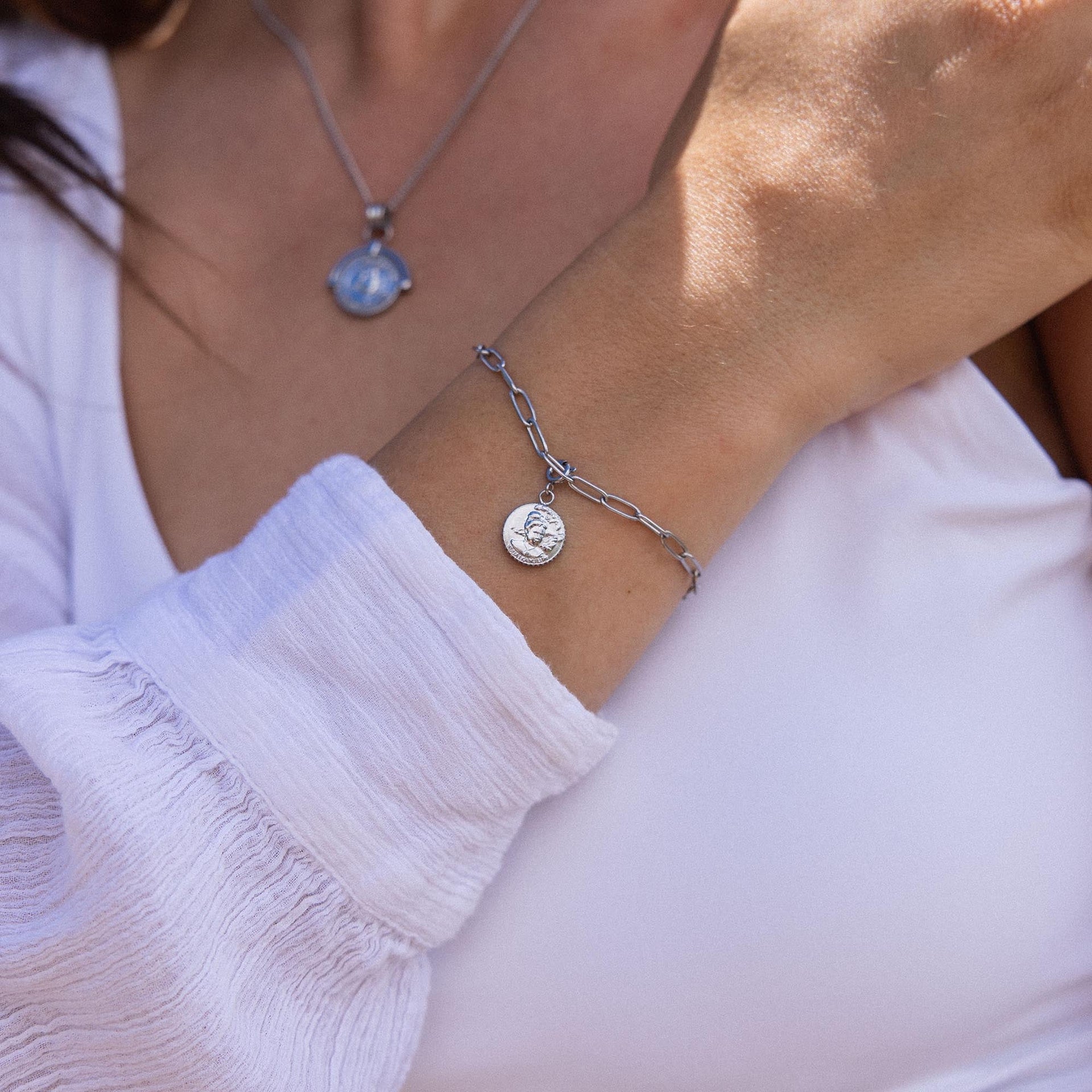 Silbernes Armband mit Münzanhänger, getragen auf zartem Handgelenk, PURELEI Stil.