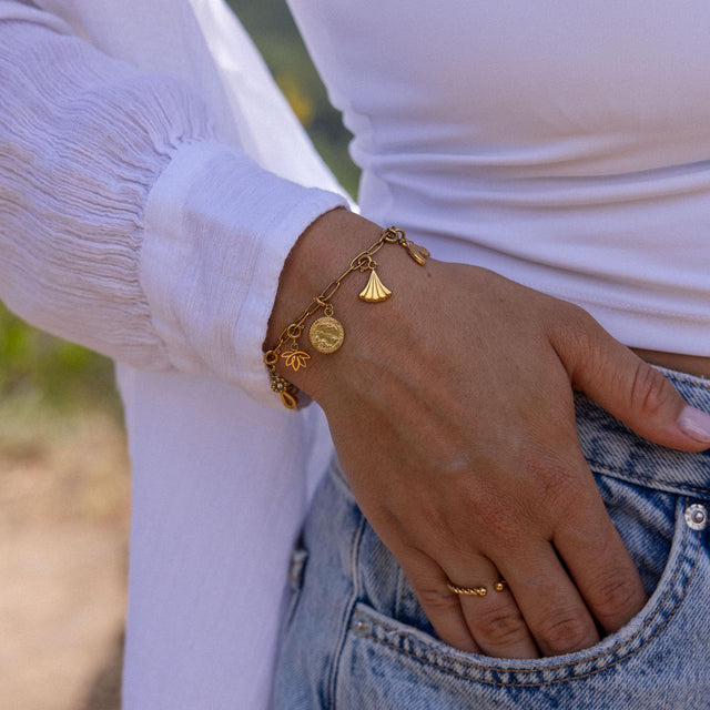 Roségoldenes Armband mit Muschel- und Blumenanhängern, getragen am Handgelenk, PURELEI.