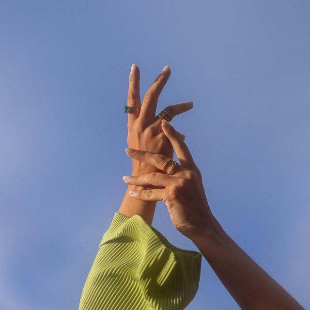 Hände mit goldenen Ringen vor blauem Himmel, PURELEI inspiriert.