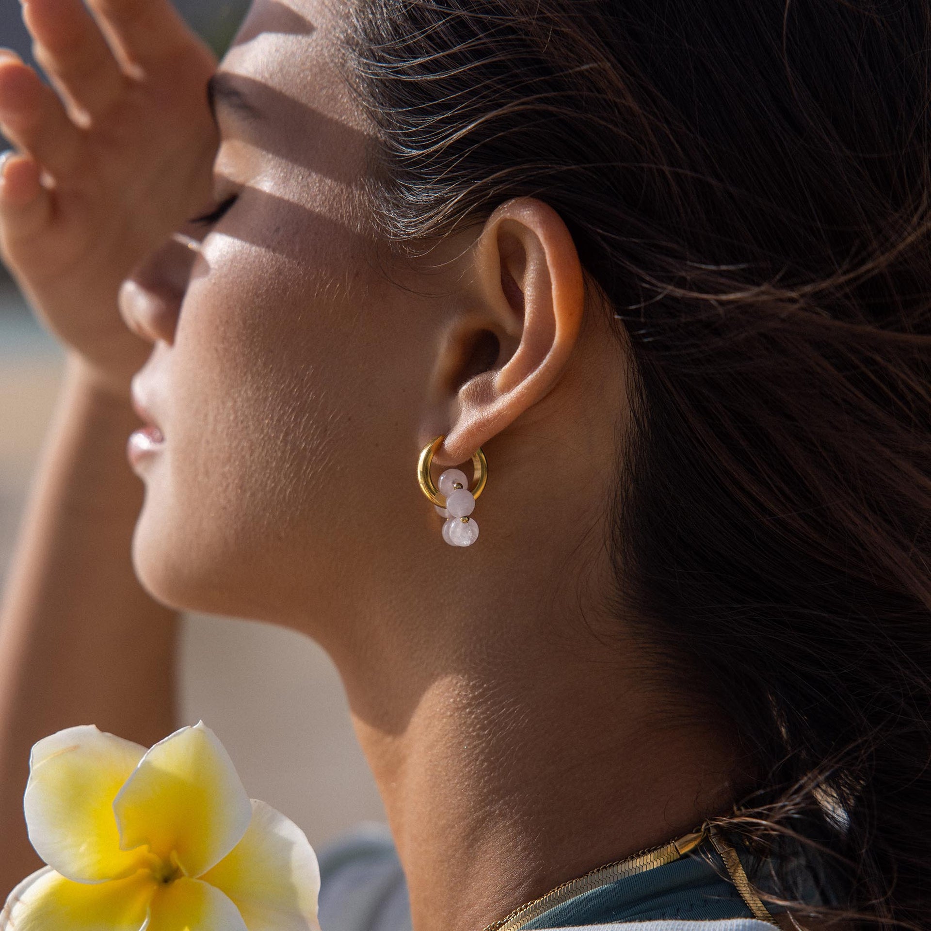 Goldene Creolen mit weißen Perlen, PURELEI, in warmem Licht, elegant und feminin.