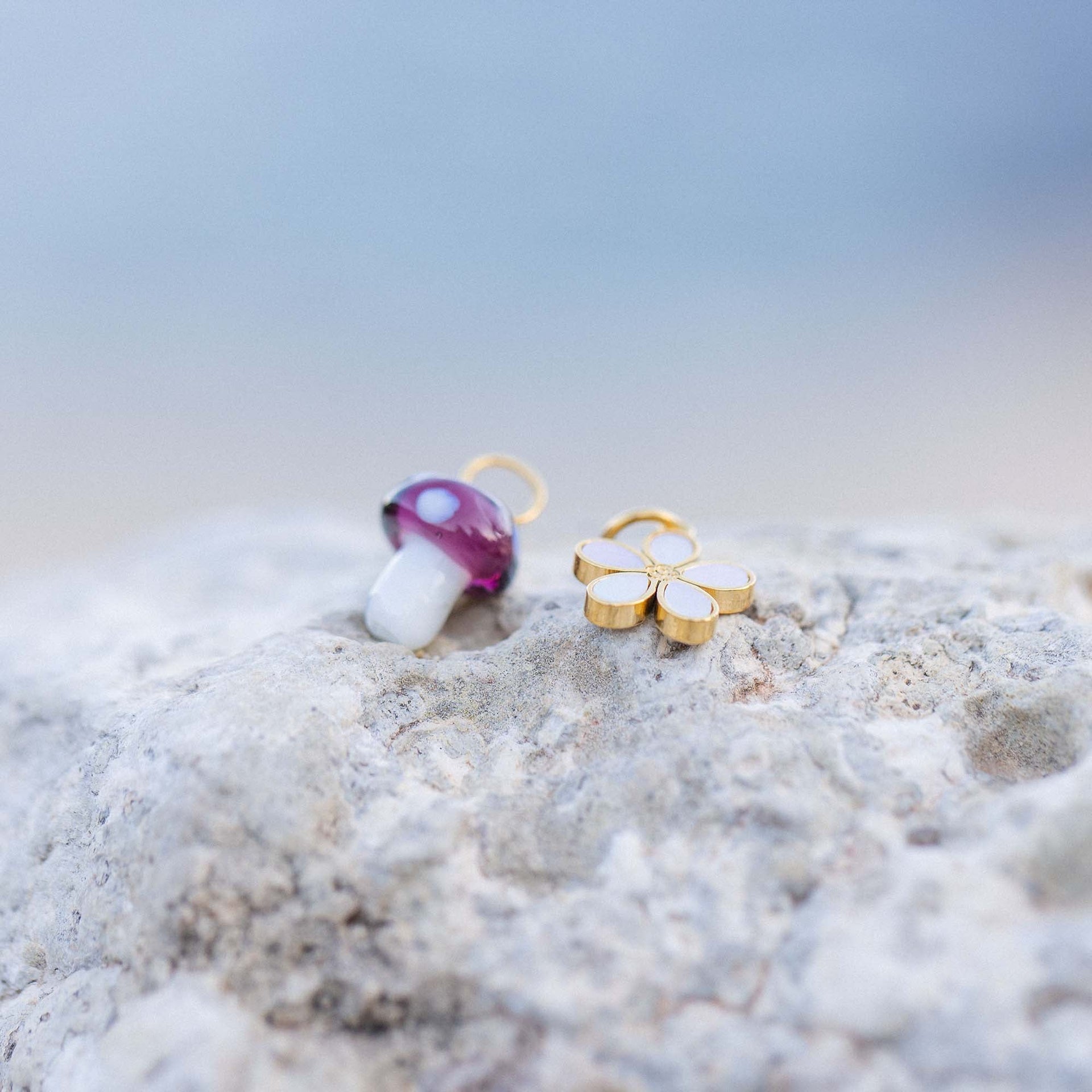 PURELEI Blumen Charm aus 18K vergoldetem Edelstahl mit Perlmutt, zart auf hellem Stein inszeniert.