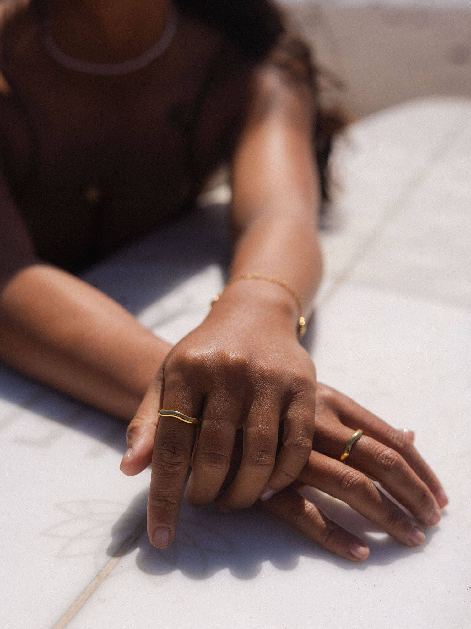 PURELEI Nakuna Ring in 18K Gold mit geschwungener Form, getragen an sonnengebräunter Hand, elegant und puristisch.