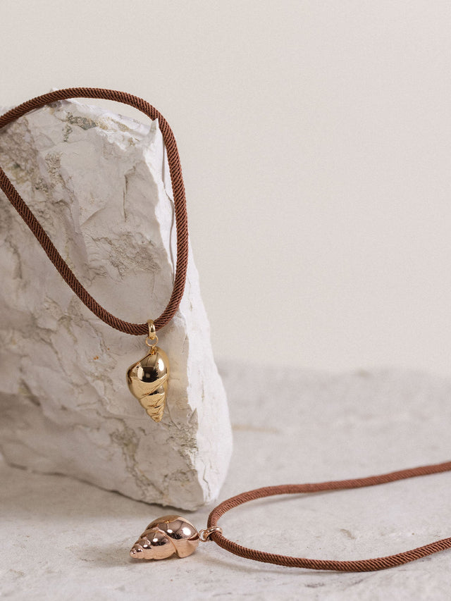 Oceanside Kette von PURELEI mit vergoldetem Muschel-Anhänger an gedrehtem, dunkelbraunem Band, elegant und natürlich.