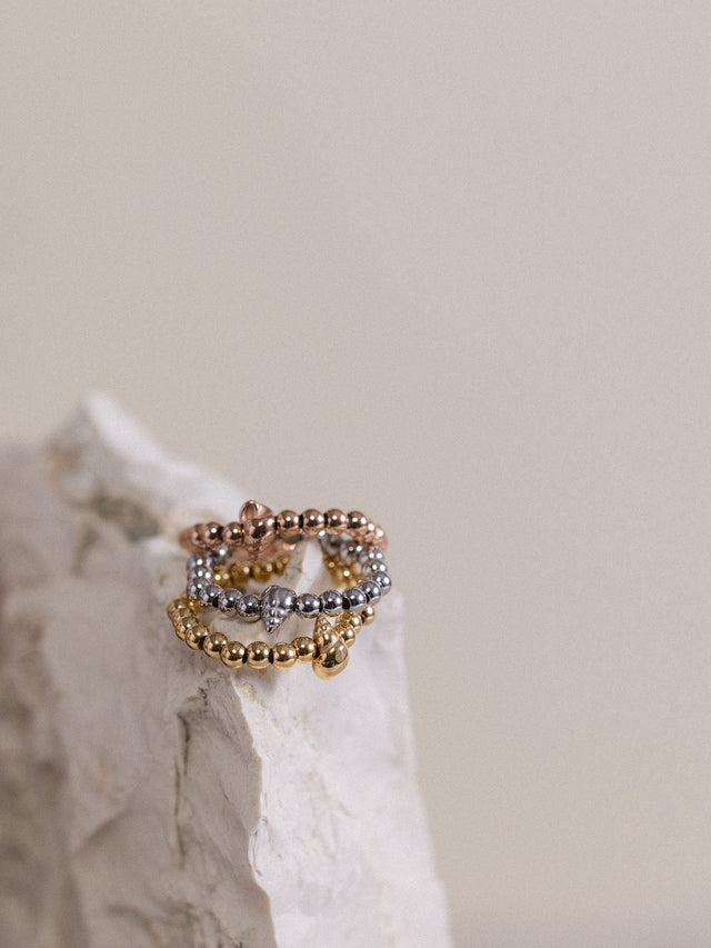 Oceanside Ring von PURELEI in Gold, Silber und Roségold mit Muschel-Detail, elegant auf hellem Stein arrangiert.