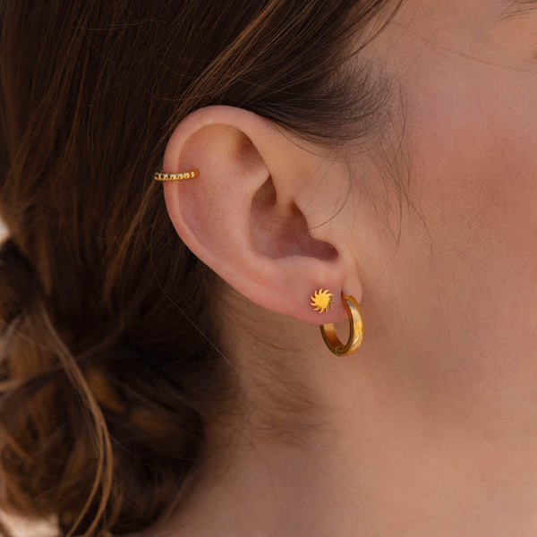 Goldene Creolen und Ohrstecker mit Sonnenmotiv von PURELEI, elegant und feminin.