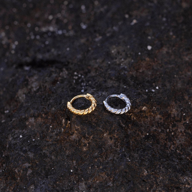 PURELEI Rope Piercing in Gold und Silber mit gedrehtem Design auf rauem Lavagestein, elegant und nickelfrei.