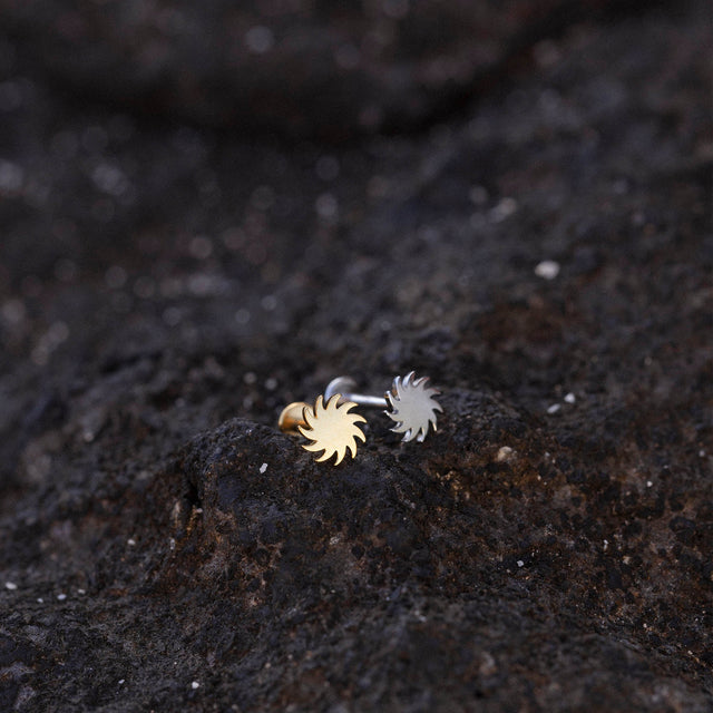Sun Piercing von PURELEI, nickelfrei, gold- und silberfarbenes Sonnenmotiv auf dunklem Lavagestein, elegant und natürlich.
