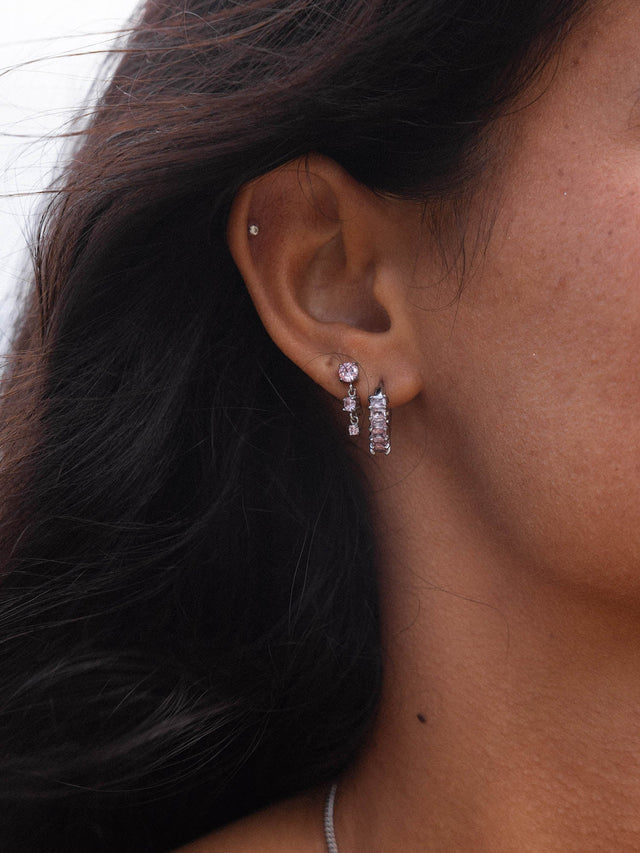 Silberne Ohrringe mit funkelnden Steinen, getragen von einer Frau, PURELEI inspiriert.