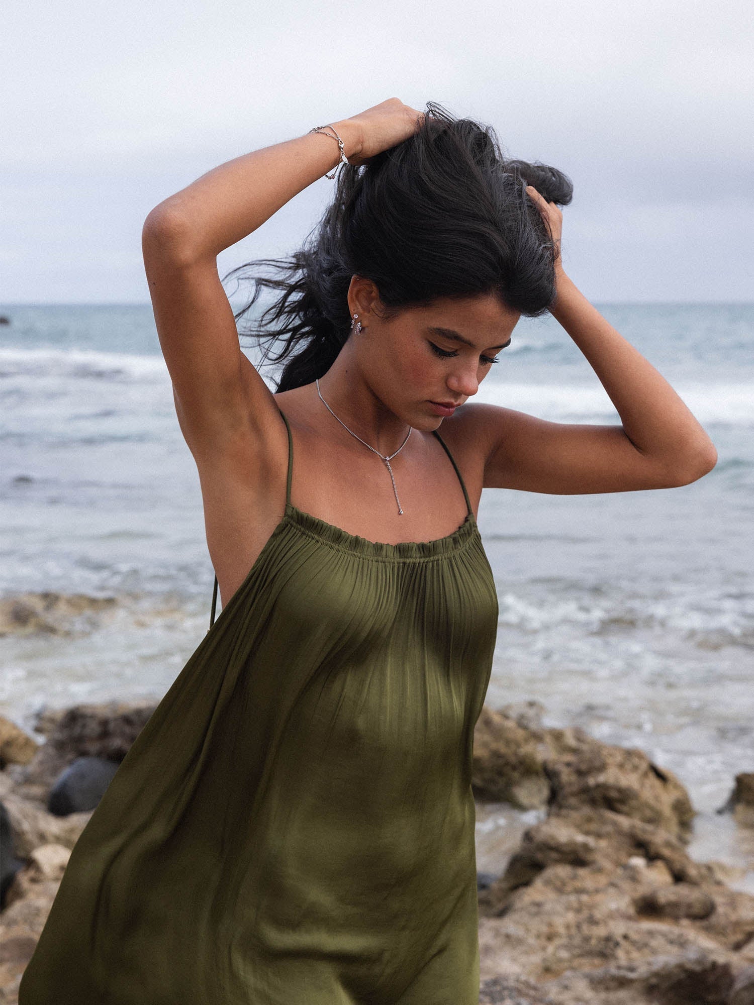 Elegante PURELEI Kette mit feinem Anhänger, getragen am Strand, umgeben von sanften Wellen.