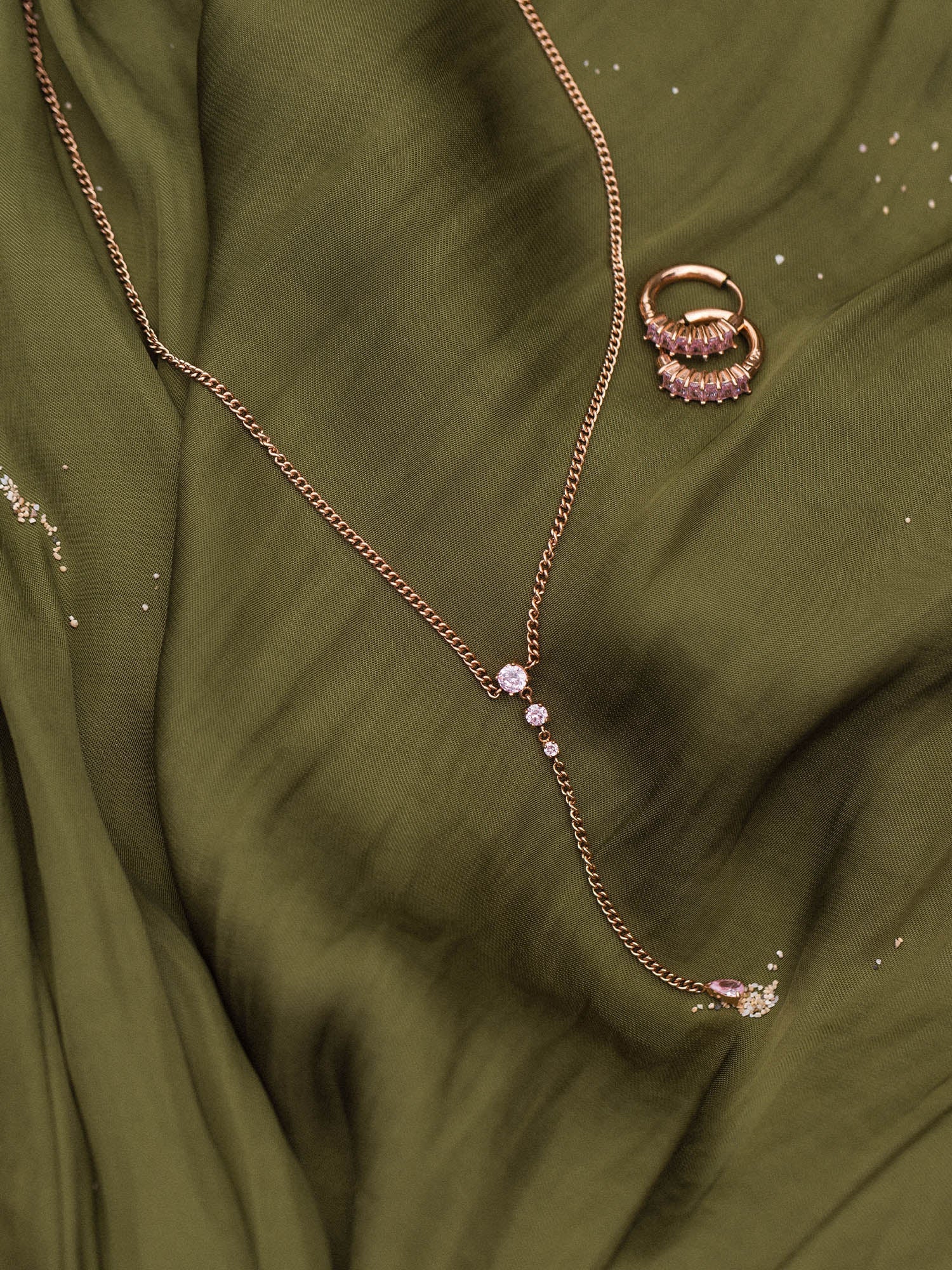 Zarte Kette und Ring aus Roségold auf grünem Stoff, PURELEI inspiriert.