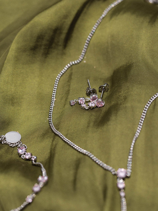 Silberne Kette und Ohrringe auf grünem Stoff, PURELEI inspiriert.