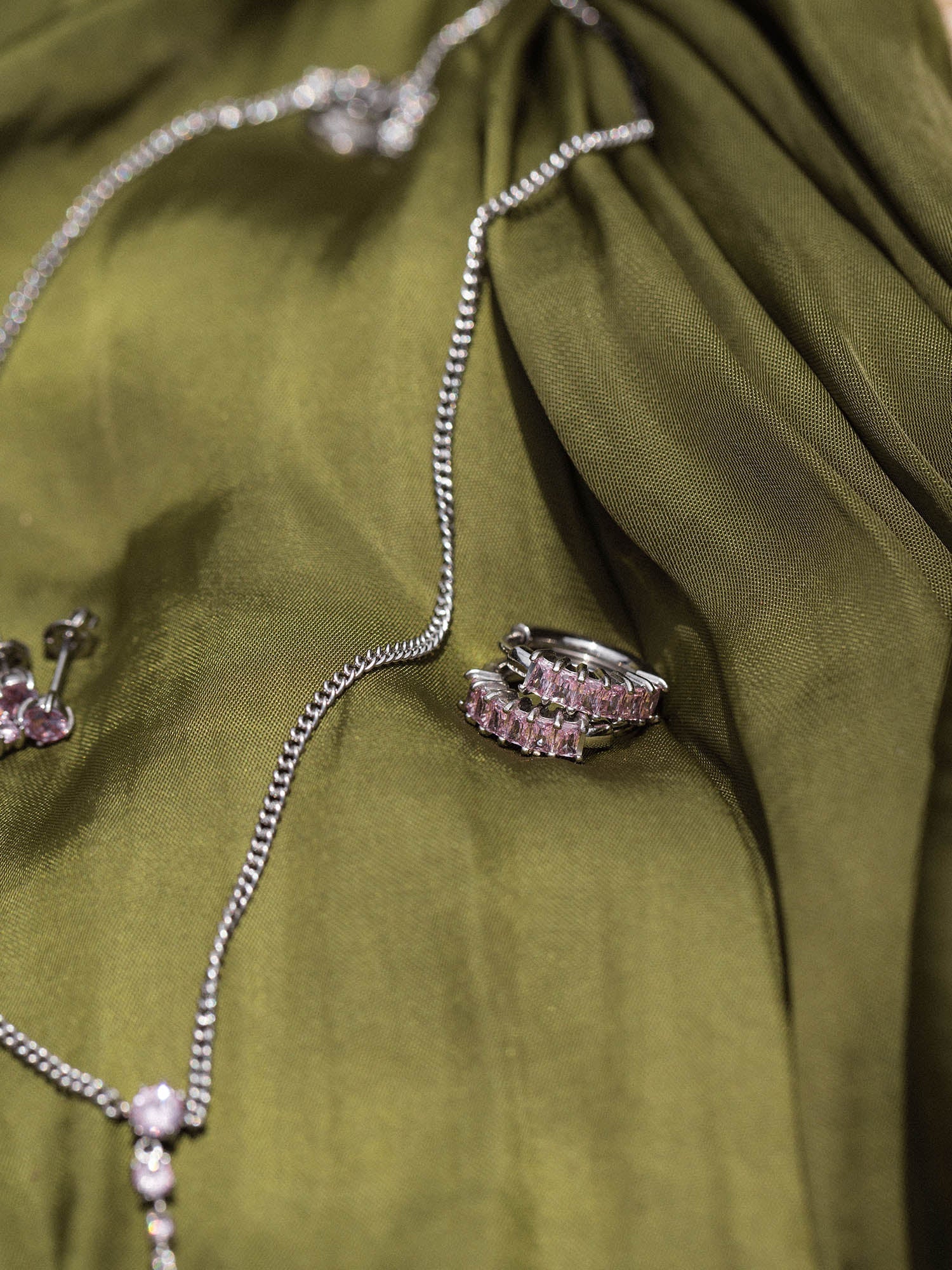 Silberne Kette und Ring auf grünem Stoff, elegant und zeitlos, von PURELEI.