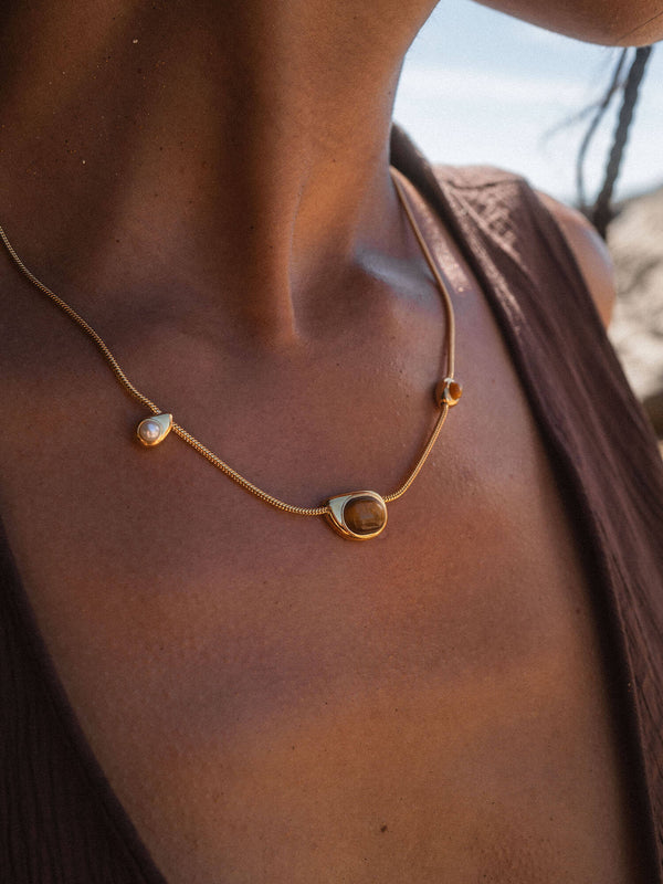 Elegante PURELEI Kette aus Roségold mit Muschelanhänger, getragen auf bronzefarbenem Hautton.