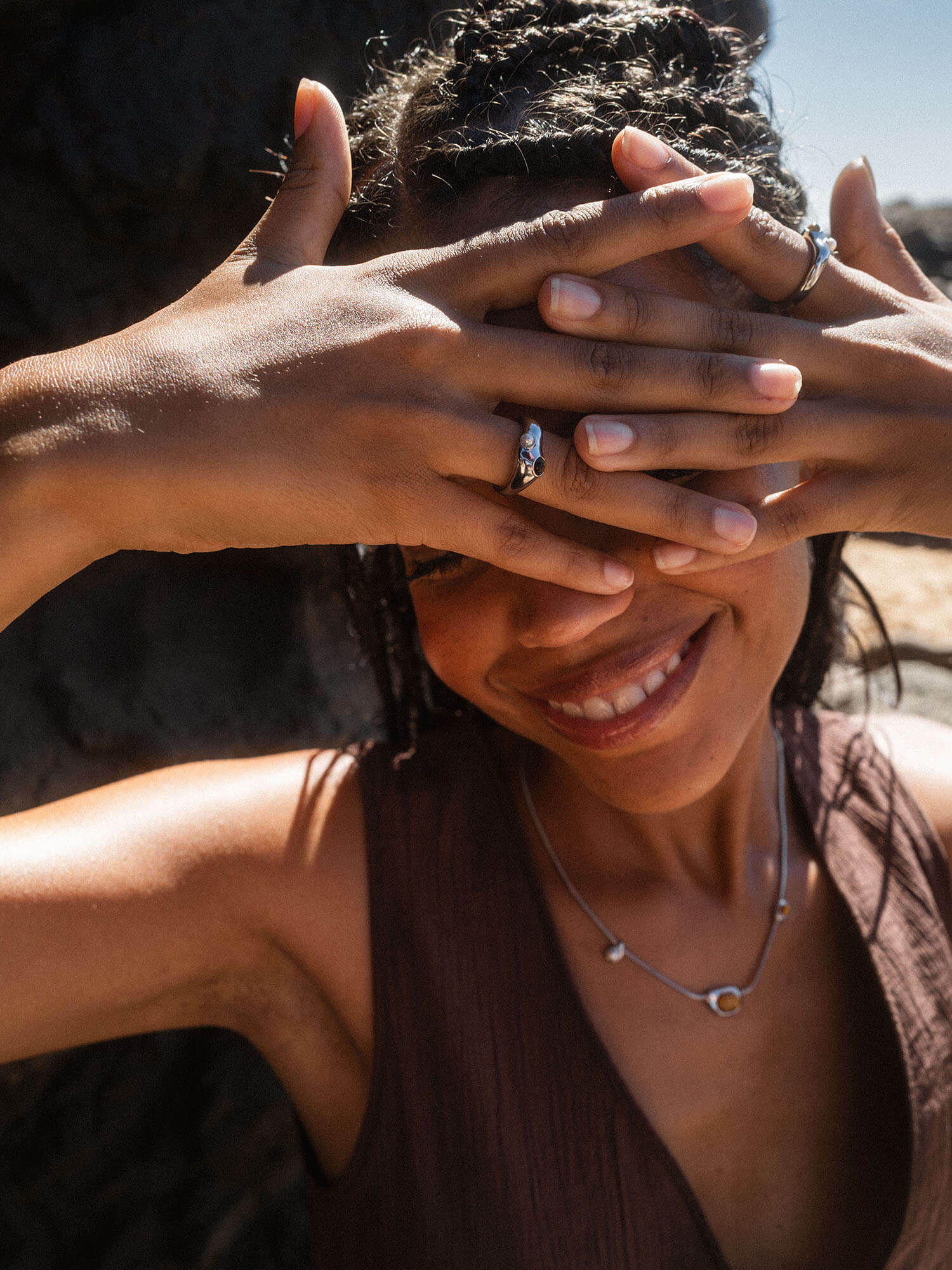 Silberne Ringe und Kette von PURELEI, getragen in warmem Licht, lächelnde Frau mit braunen Händen.