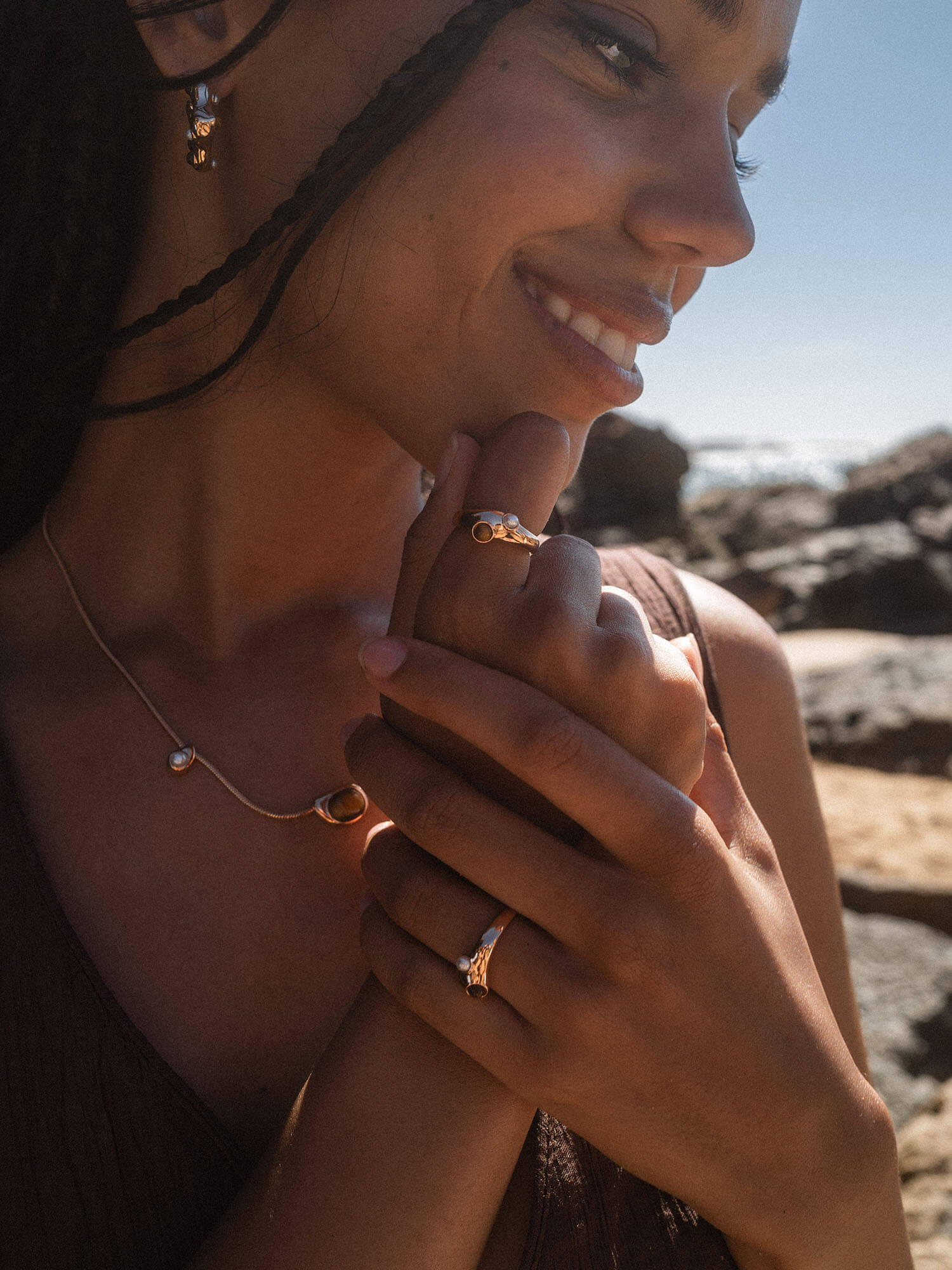 Silberne PURELEI Schmuckstücke, elegant und feminin, am Handgelenk und Ohr, in warmem Licht.