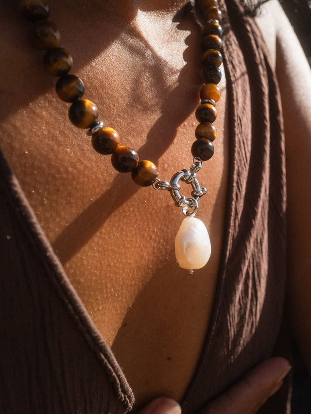 PURELEI Organic Pearl Charm mit Barockperle an brauner Edelstein-Kette, feminin und natürlich im warmen Sonnenlicht.