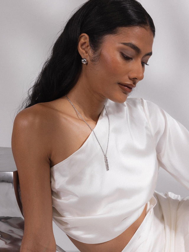 PURELEI Aquarius Letter Charm aus silbernem Edelstahl, filigran und elegant am Dekolleté getragen.