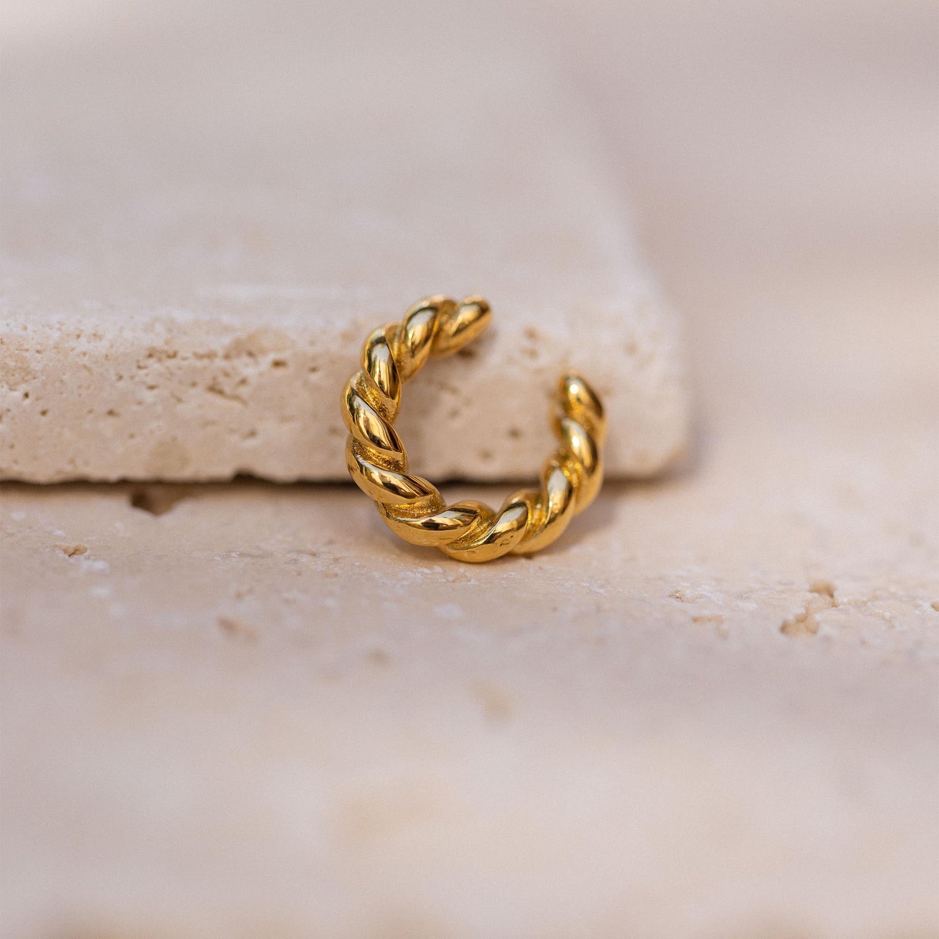 Goldene, gewundene Creole auf hellem Stein, inspiriert von PURELEI.