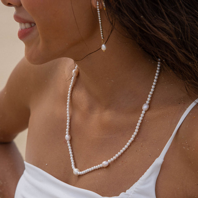 Perlenkette von PURELEI, elegant und feminin, in strahlendem Weiß, am Hals getragen.