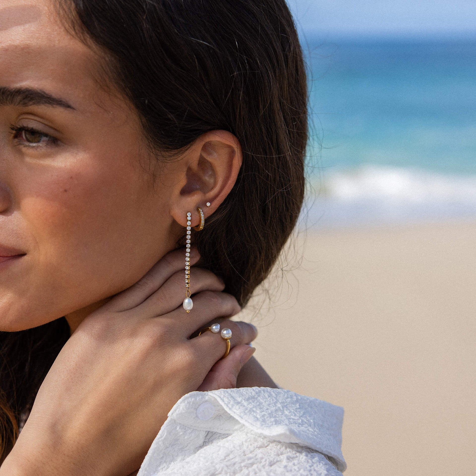 Elegante, silberne Ohrringe mit Perlen und zarten Details, getragen am Strand – PURELEI.