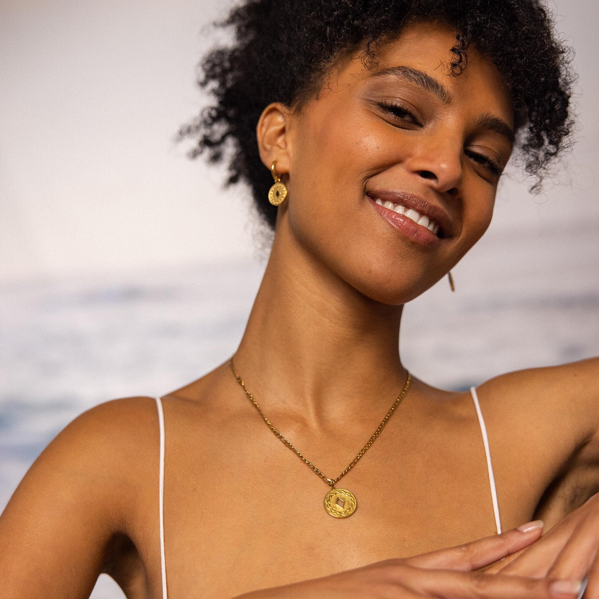 Roségoldene Kette und Ohrringe von PURELEI, elegant und feminin, mit sonnigem Lächeln getragen.