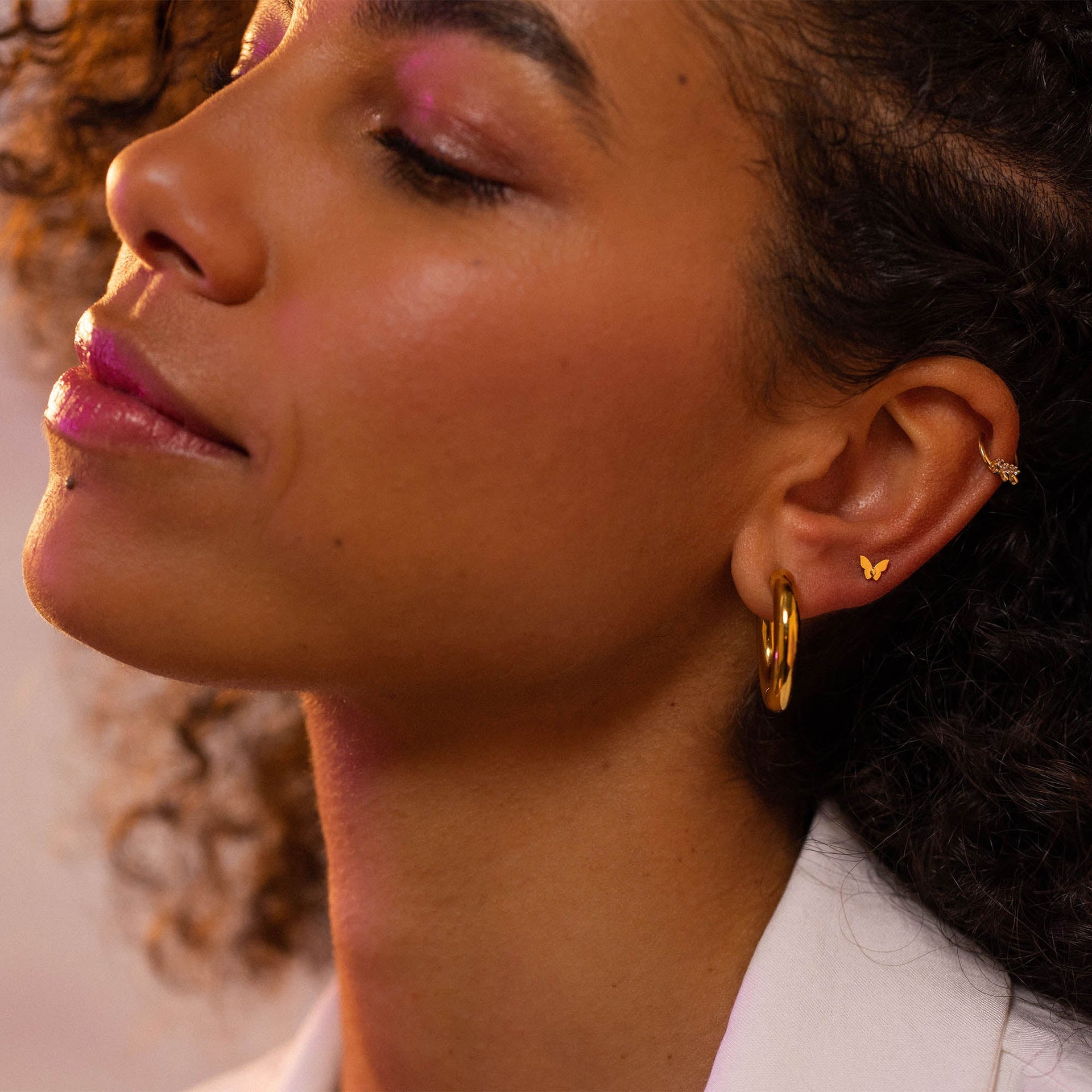 Roségoldene Creolen und zarte Schmetterlingstecker von PURELEI, elegant und feminin.