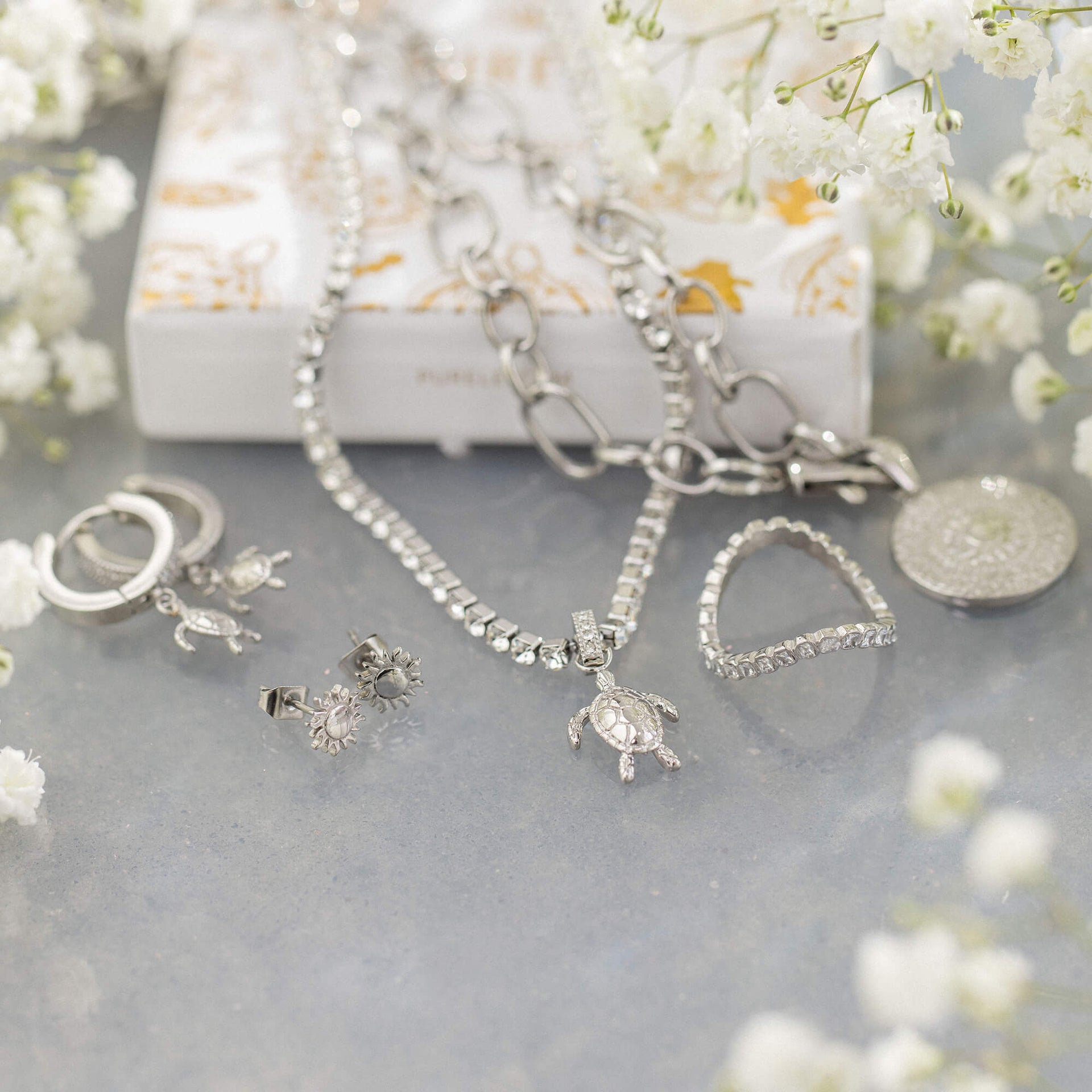 Silberne Schmuckstücke von PURELEI mit Schildkröten- und Sonnenmotiven, elegant arrangiert.