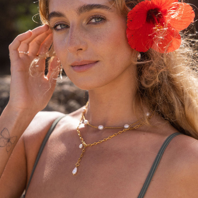 PURELEI Zodiac Charm Kette in Gold mit Süßwasserperlen, leicht und elegant, getragen bei sonnigem Outdoor-Moment