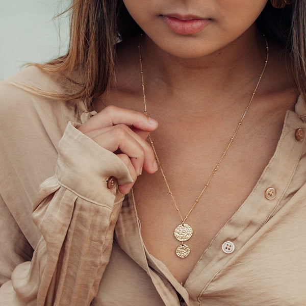 Malihini Coin Kette von PURELEI in 18K Gold, zwei strukturierte Anhänger, elegant getragen mit natürlichem Flair.