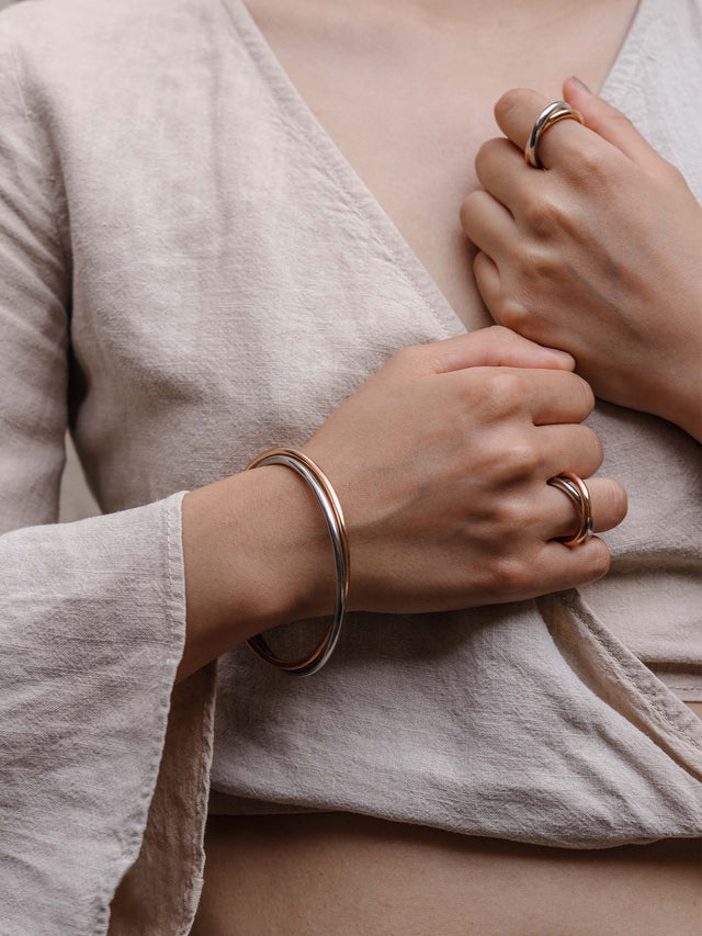Roségoldenes Armband und Ring von PURELEI, elegant und modern, getragen auf weichem Leinen.