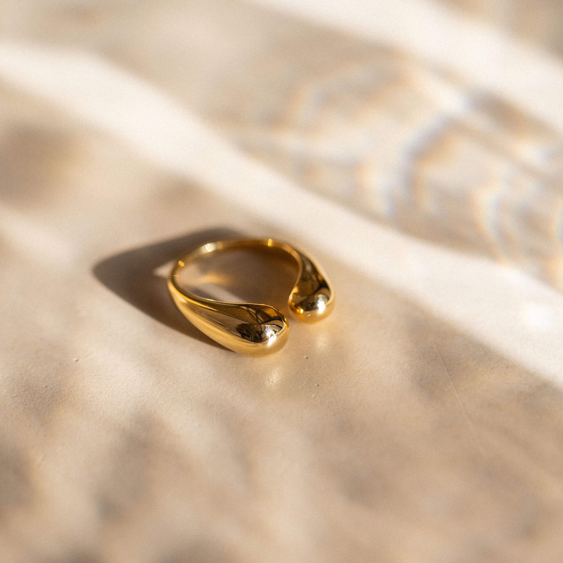 Goldener Ring mit geschwungenem Design auf sanftem Stoff, PURELEI inspiriert.