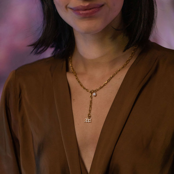 PURELEI Wassermann Zodiac Charm aus 18K vergoldetem Edelstahl an elegantem Hals in warmer Lichtstimmung